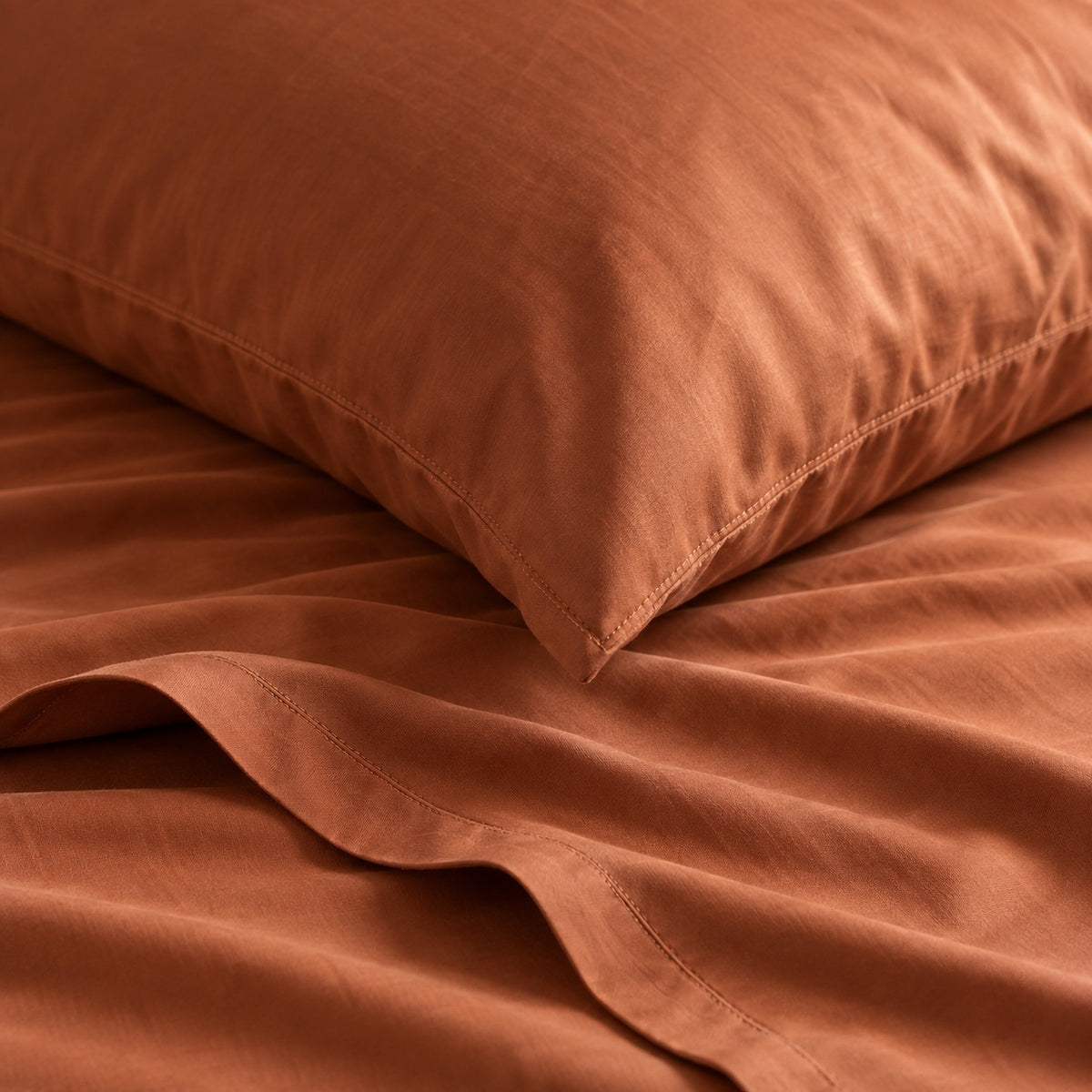 Close-up of Terracotta cotton sateen fabric, natural folds and a stitched pillowcase hem